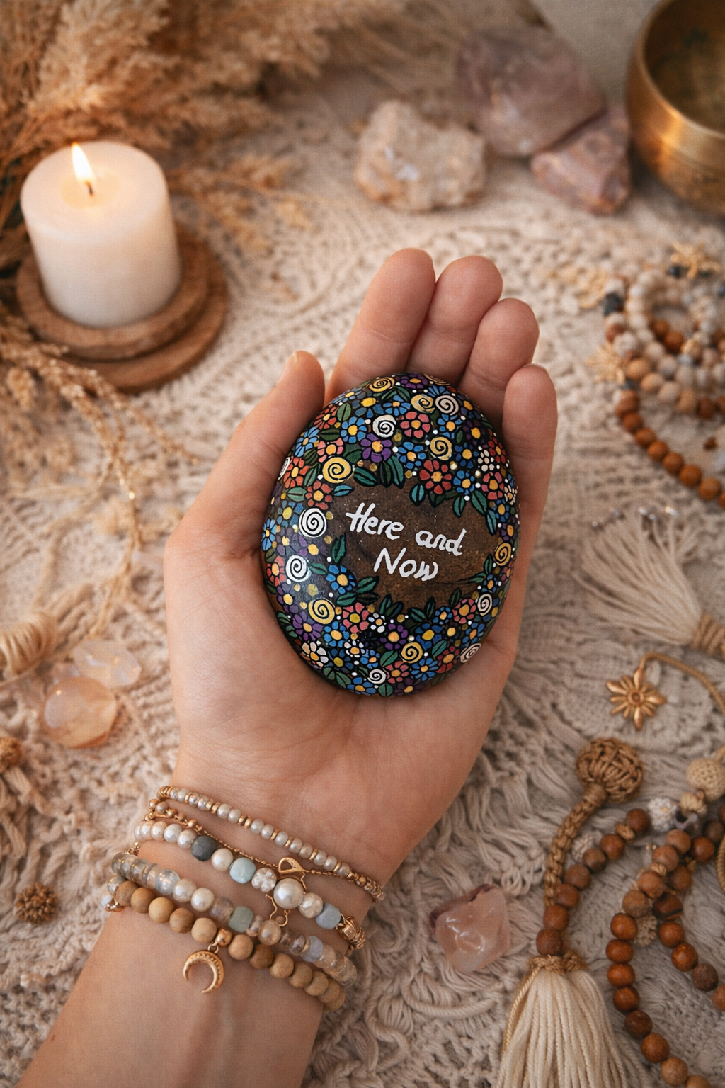 Hand painted stone with colorful floral pattern and “Here and Now” mindfulness affirmation